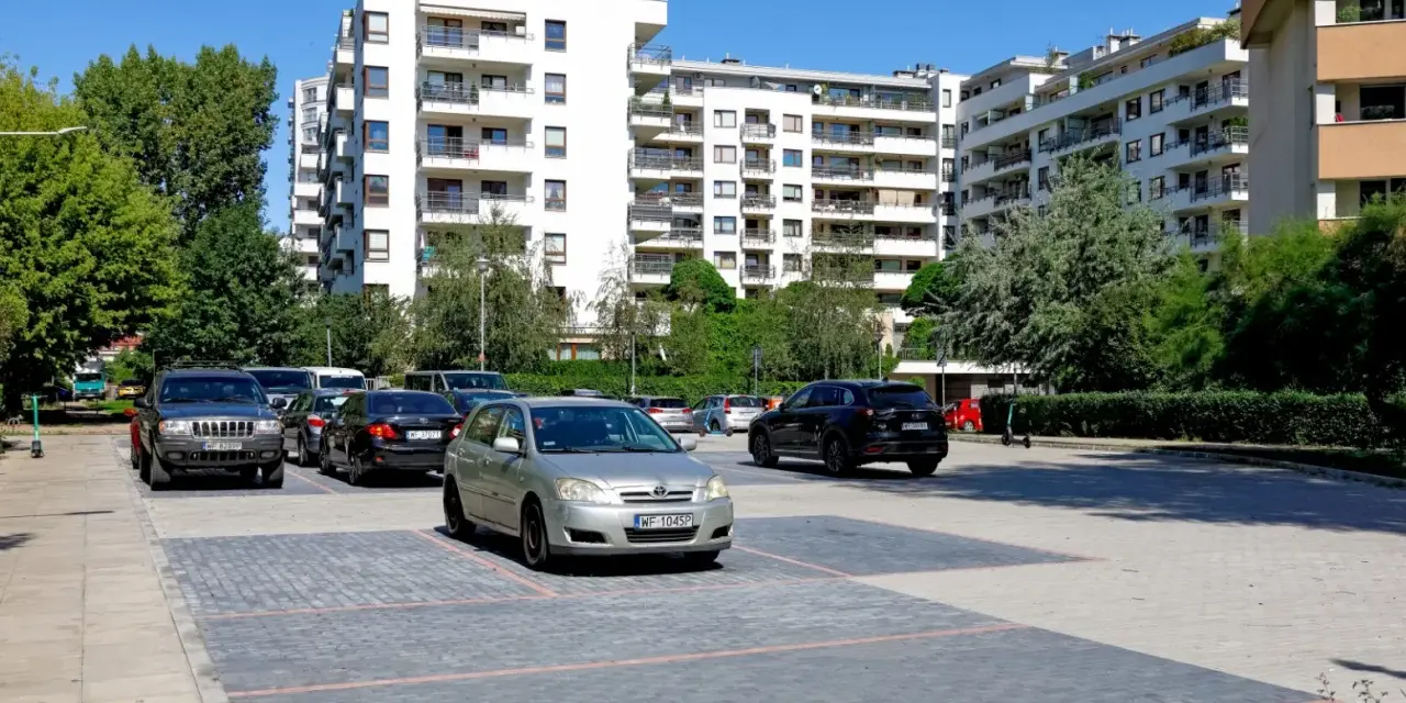 Nowoczesne osiedle w Warszawie, parking z samochodami. Zastanawiasz się, ile kosztuje kawalerka w Warszawie?