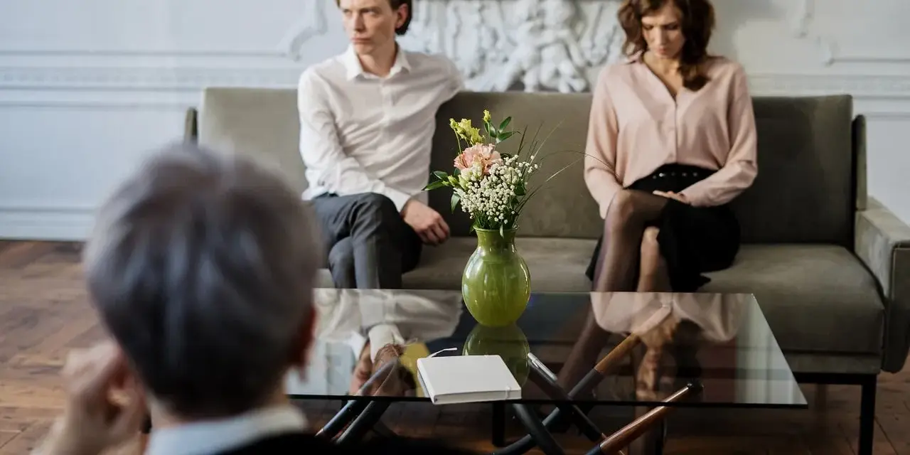 Un couple en discussion avec un avocat, cherchant une aide juridictionnelle pour leur divorce.