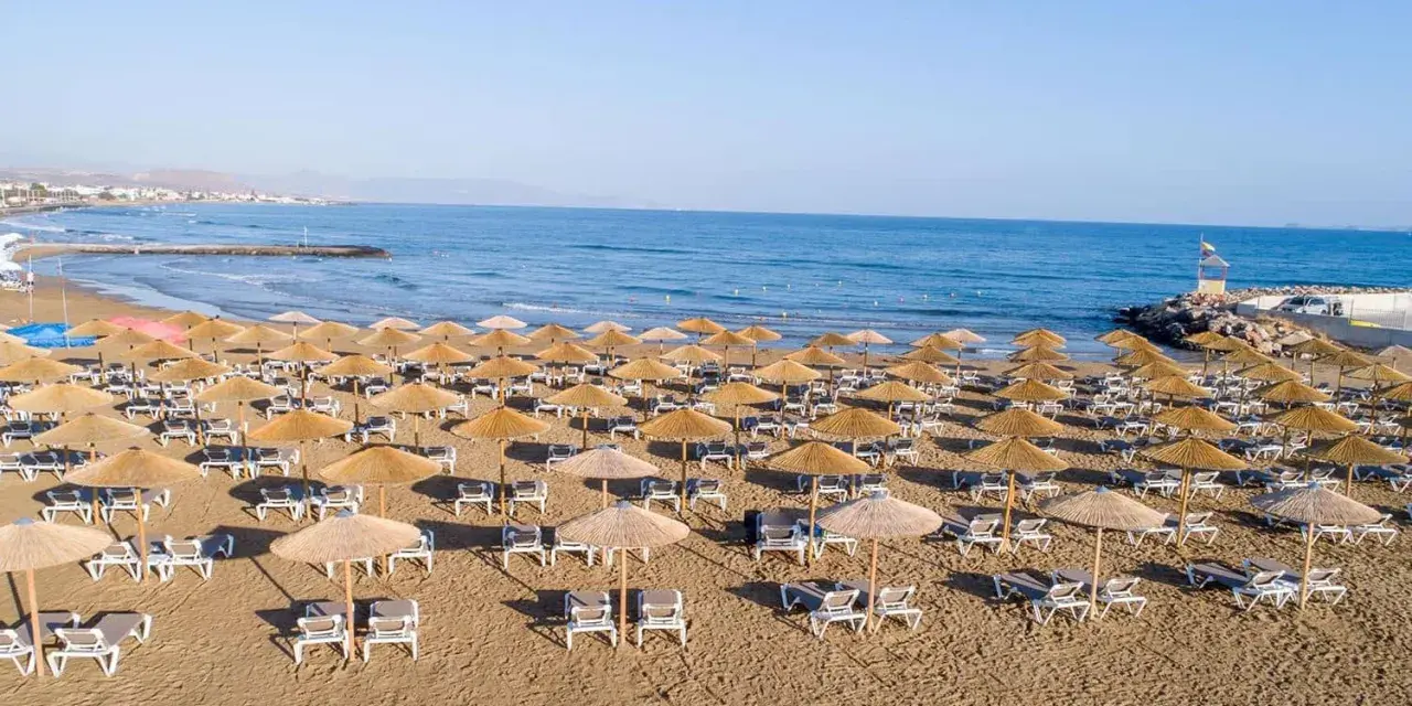 Plaża sol marina beach crete z rzędami leżaków i parasoli, gotowa na gości. Błękitne morze i niebo tworzą idealne tło.
