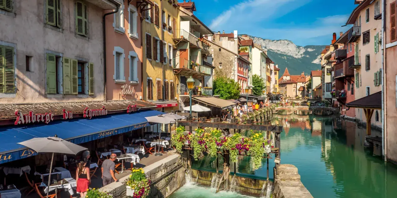 Canal animé à Annecy, avec des restaurants en terrasse et des fleurs colorées. Idéal pour découvrir les choses à faire à Annecy.