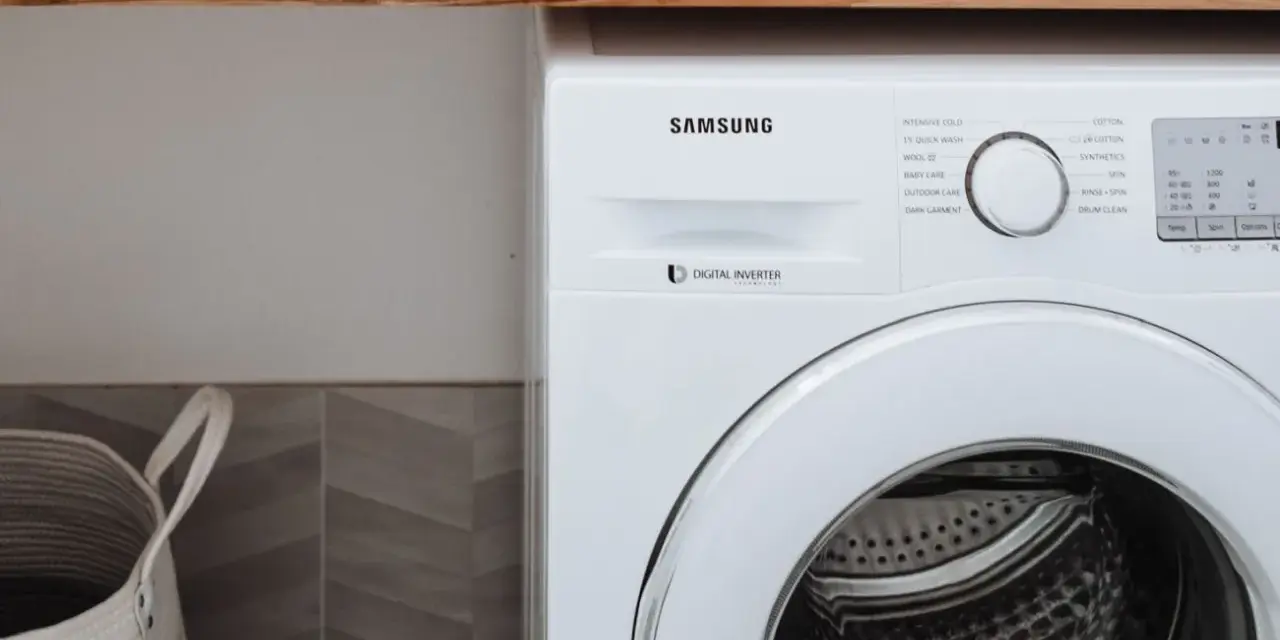 Biała pralka Samsung z technologią Digital Inverter. Obok kosz na pranie.