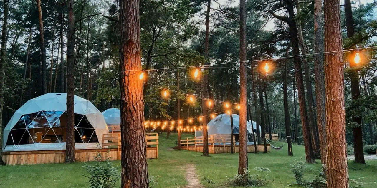 Domek w lesie, idealny na camping w Warszawie. Girlanda świateł tworzy magiczny klimat.