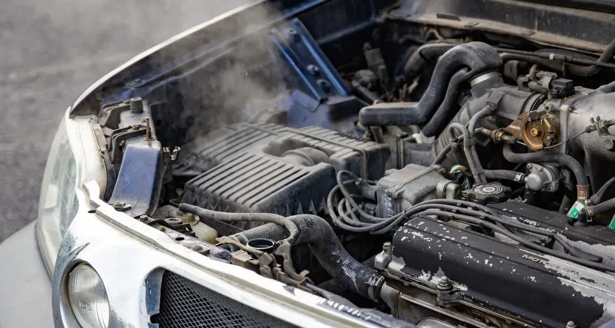 Steam rises from an overheated car radiator, indicating a potential engine problem.