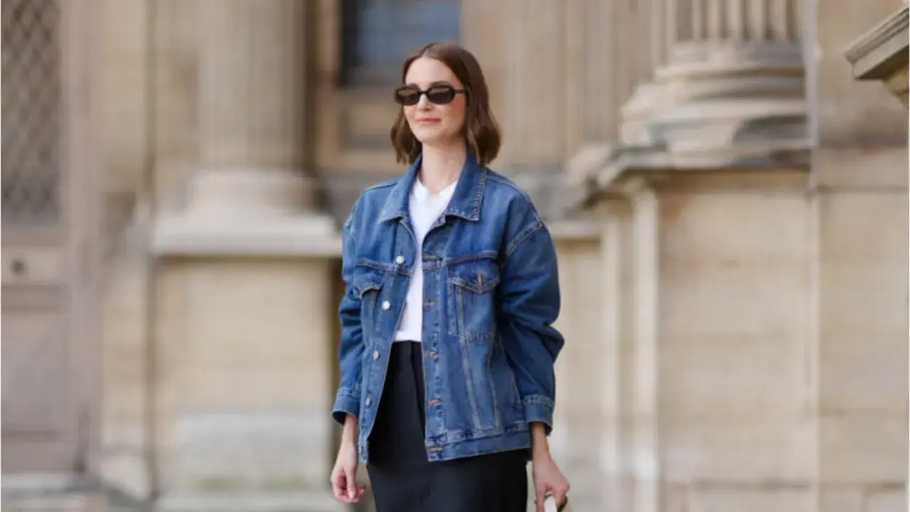 Donna con occhiali da sole indossa un outfit giacca jeans donna, t-shirt bianca e gonna nera.