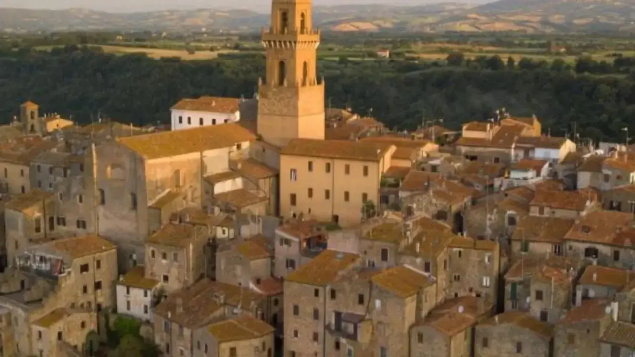 Pitigliano, la "piccola Gerusalemme", si staglia su una rupe tufacea, con le sue case antiche e la torre campanaria che domina il paesaggio.