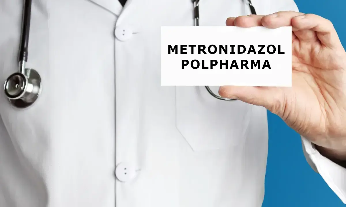 Lekarz w białym kitlu trzyma kartkę z napisem "METRONIDAZOL POLPHARMA". Metronidazol bez recepty to lek, który może pomóc w leczeniu infekcji.
