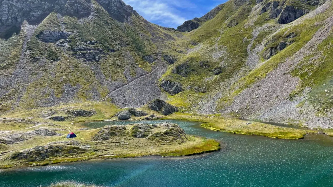 Un accampamento solitario ai laghetti di Ponteranica, tra montagne verdi e acque cristalline.