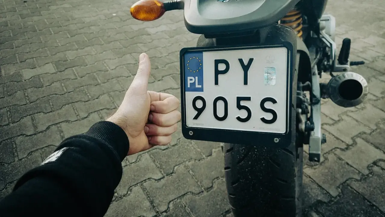 Kciuk w górę przy rejestracji starego motocykla z dokumentami. PY 905S.