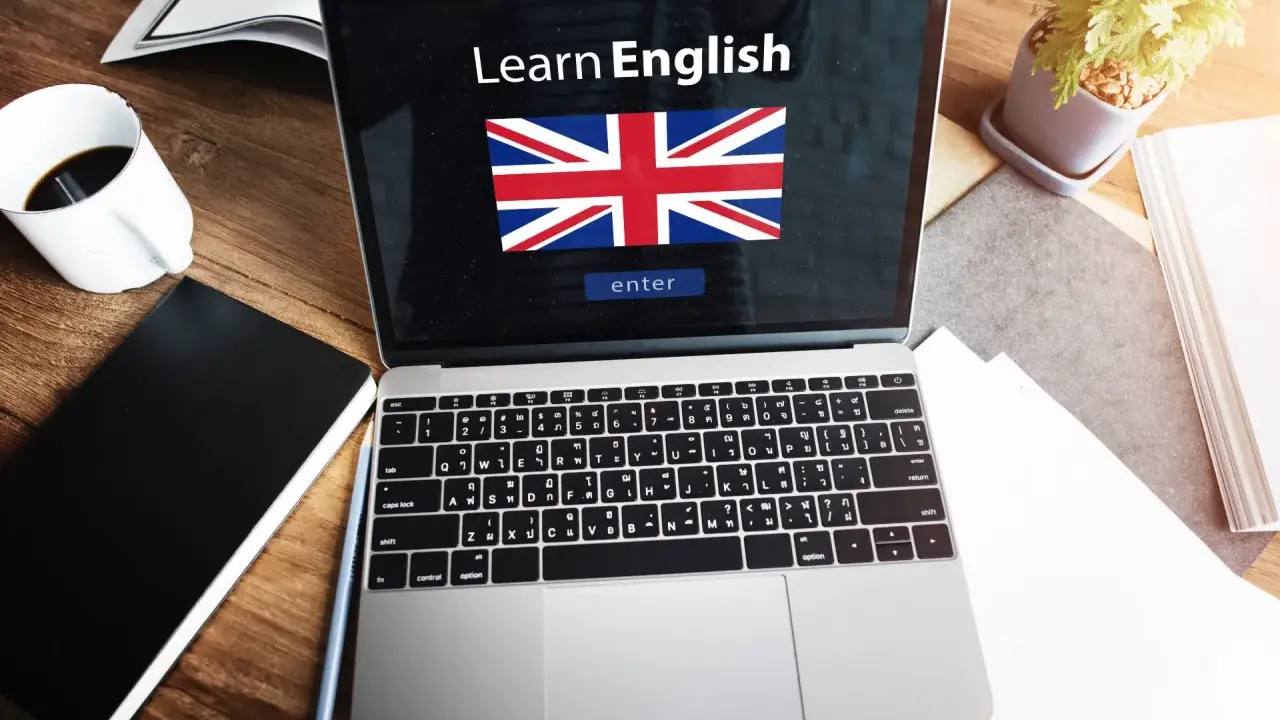 Laptop z napisem "Learn English" i flagą Wielkiej Brytanii. Obok kawa, notatnik i roślina. Idealne do nauki fce use of english.