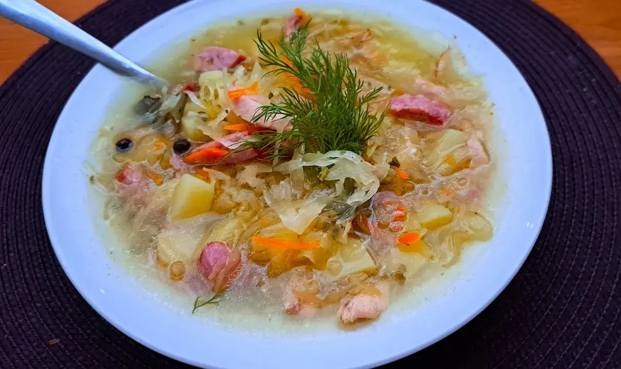 Syta zupa z kiszonej kapusty z ziemniakami i kiełbasą, ozdobiona koperkiem. Pyszne dania z kapusty na zimowe wieczory.