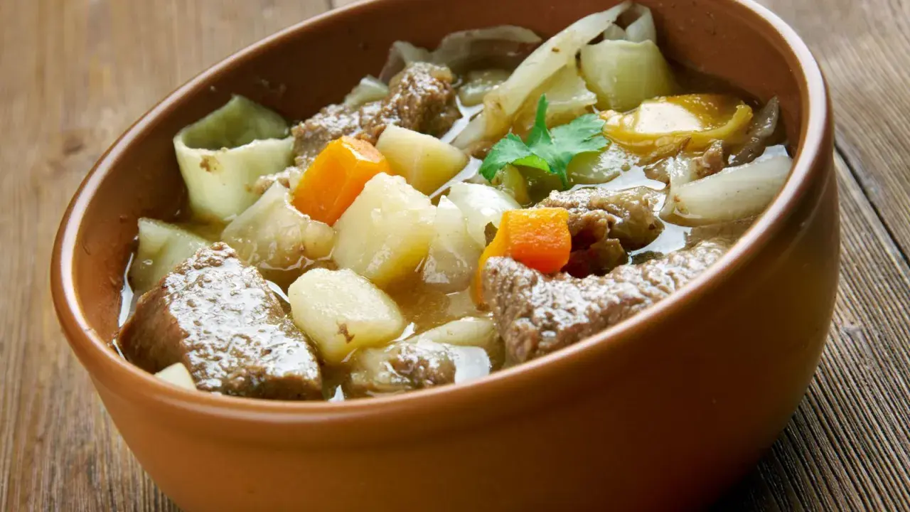 Un copieux plat typique des Pyrénées, un ragoût de bœuf avec pommes de terre et carottes, servi dans un bol en terre cuite.