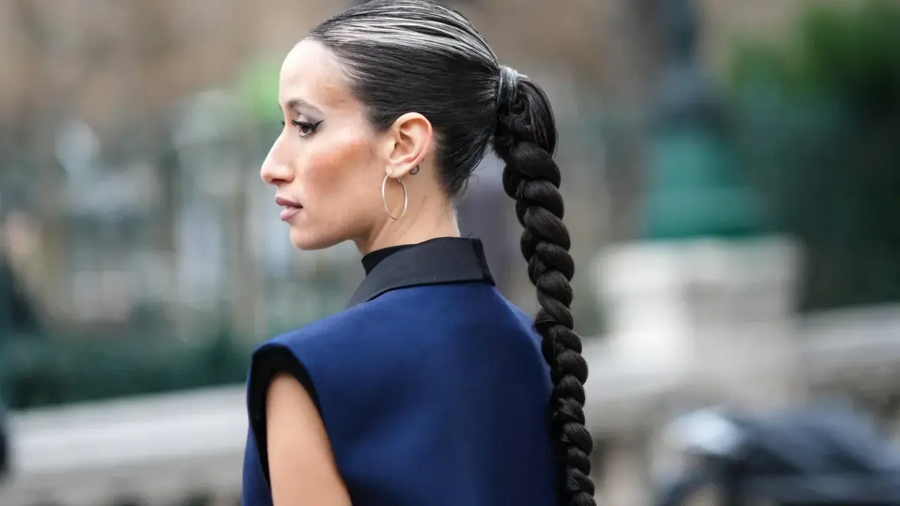Eine Frau mit einem dicken, geflochtenen Zopf und Highlights. So kann man haare einfach stylen für einen eleganten Look.