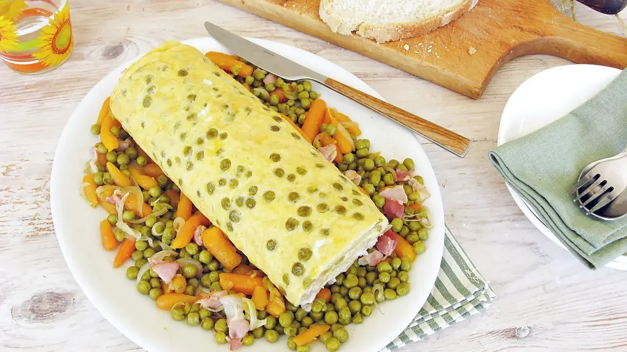 Rotolo di frittata dorato adagiato su un letto di piselli e carote. Un piatto semplice e gustoso, perfetto per un pasto leggero.