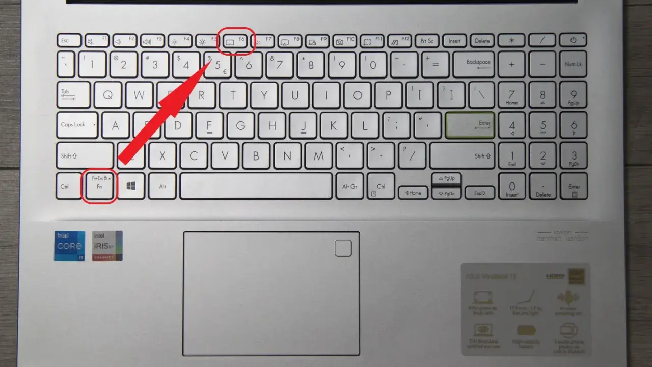 Klawiatura laptopa z podświetloną ikoną touchpada. Czerwona strzałka wskazuje klawisz Fn+Esc, który może aktywować touchpad.