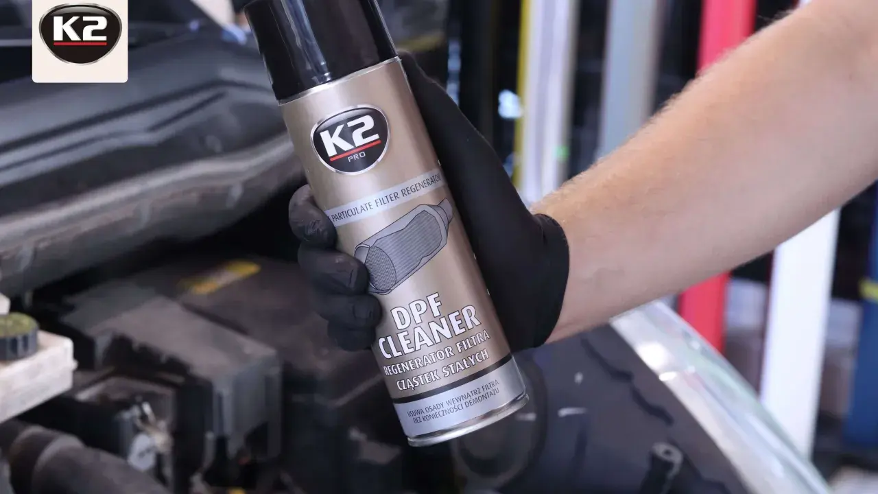 Ręka w czarnej rękawiczce trzyma puszkę K2 DPF Cleaner, zapobiegając ryzyku zapchania filtra cząstek stałych w Citroen C4.