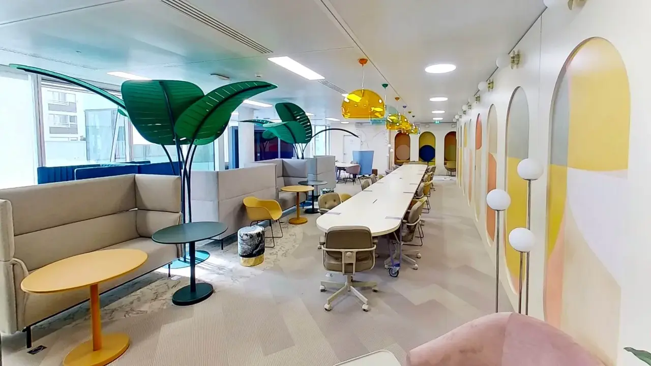 Espace de travail moderne et coloré, ce **flex office** offre des zones de réunion, des canapés confortables et des plantes décoratives pour un environnement stimulant.