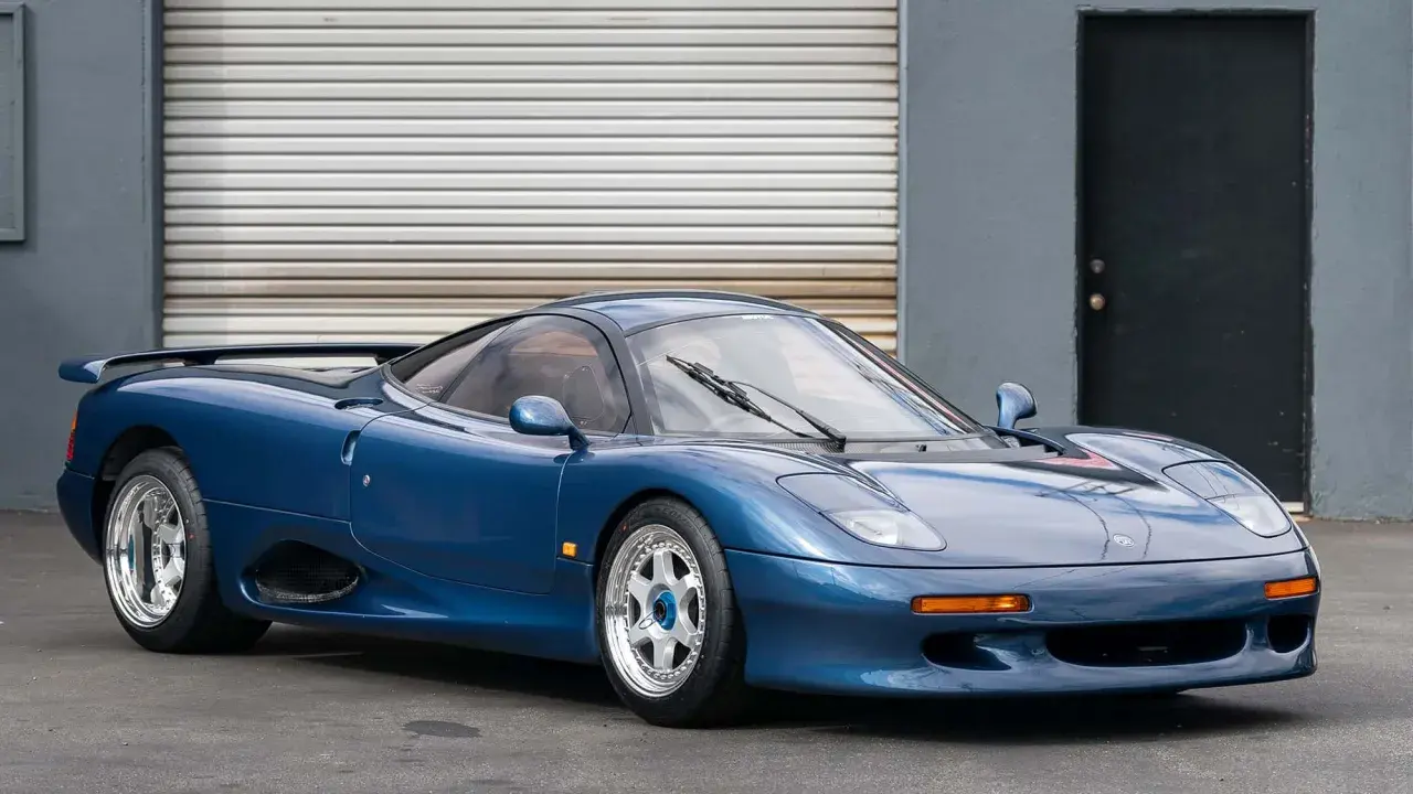 Blauer Jaguar XJR-15 Sportwagen mit auffälligem Heckspoiler und glänzenden Felgen, bereit für die Rennstrecke.