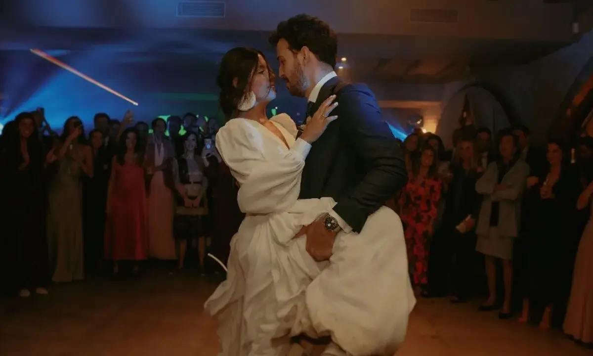 Novios bailando su vals boda, rodeados de invitados expectantes. La novia, con un vestido blanco voluminoso, es alzada por el novio.
