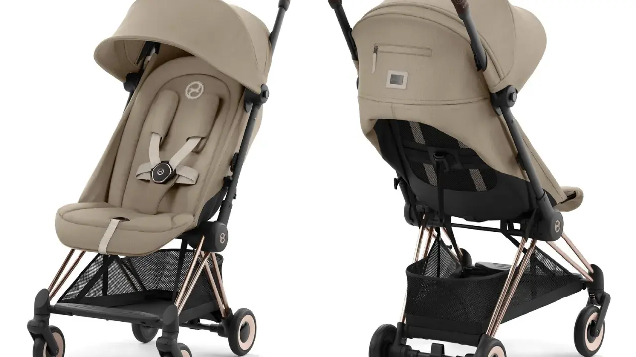 Elegancki wózek spacerowy Cybex w kolorze beżowym, z brązową rączką i złotymi elementami. Idealny na spacery.