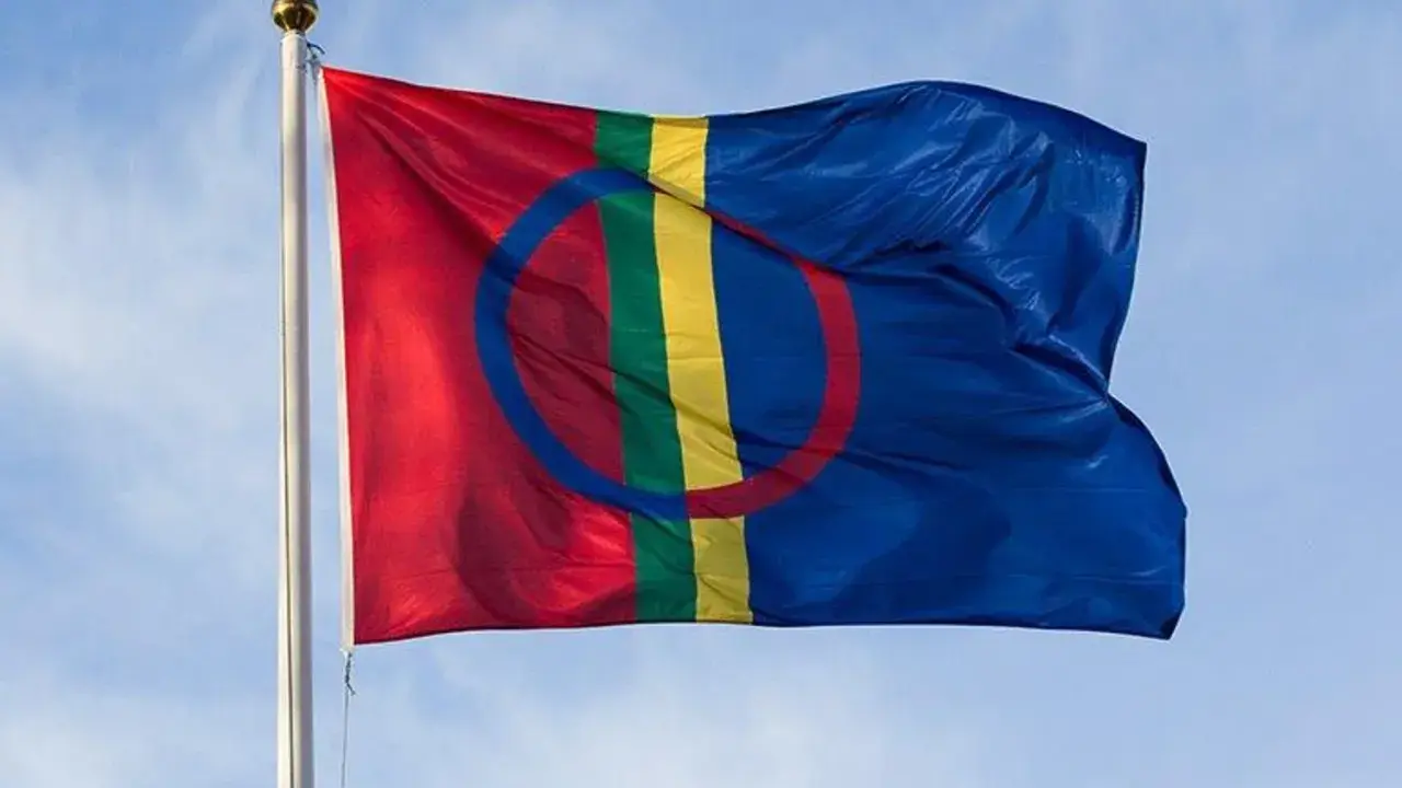 Samiska flaggan vajar stolt mot en blå himmel, en symbol för samiska nationaldagen och ett folk med djupa rötter.