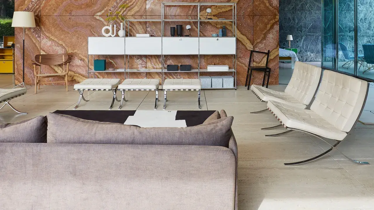 Soggiorno moderno con divano grigio, poltrone in pelle bianca e sgabelli, su sfondo di travertino rosso. Il **case design** è elegante e funzionale.