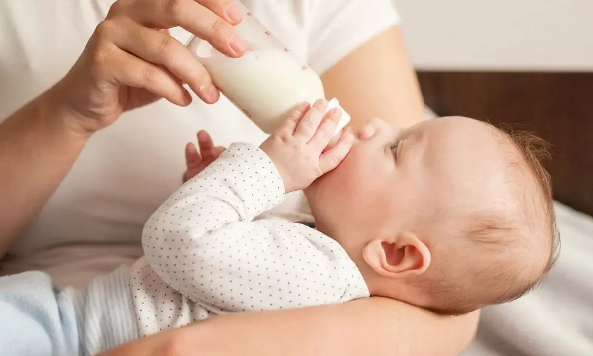 Dziecko pije mleko z butelki. Od kiedy mleko krowie zamiast modyfikowanego, maluch rośnie jak na drożdżach.