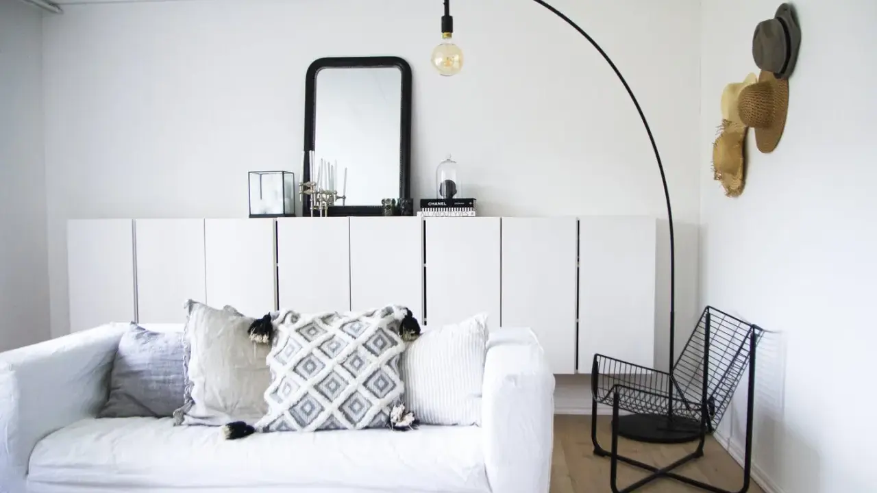 En stilren och modern manlig inredning med vit soffa, svarta detaljer och en golvlampa.