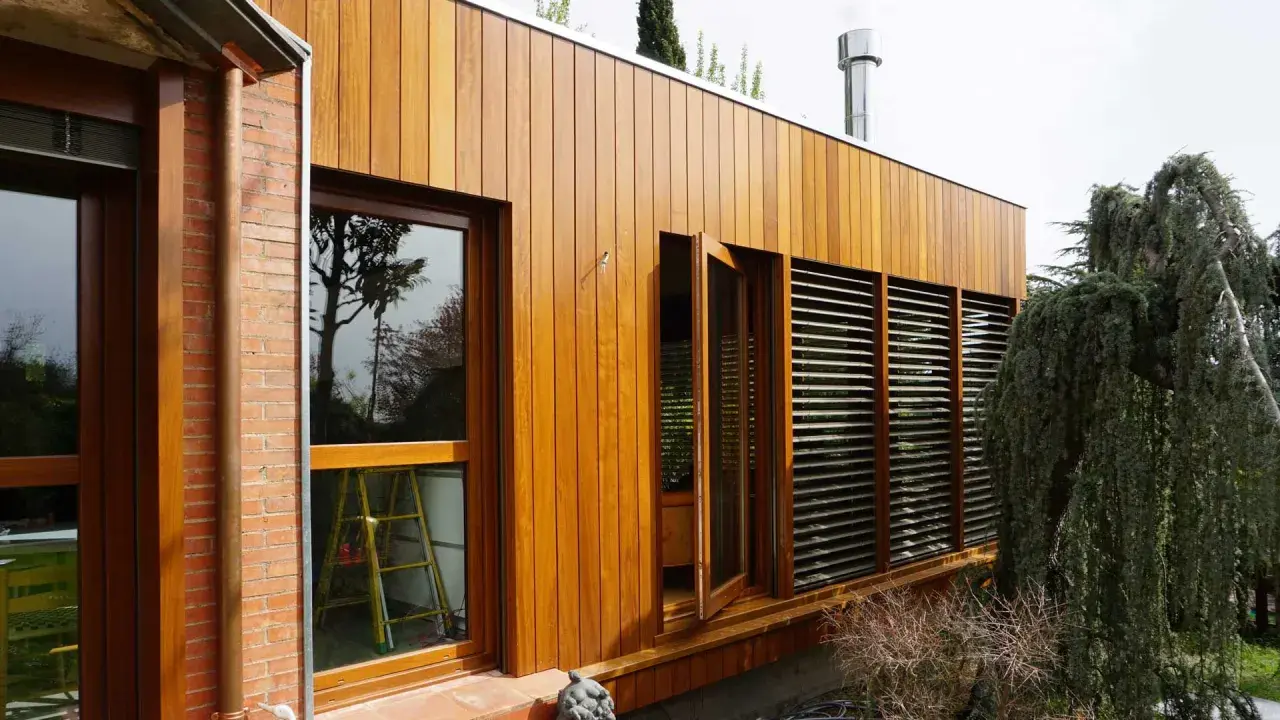 Modern house with ventanales grandes para casas, madera y ladrillo. Un árbol frondoso cuelga sobre la estructura.