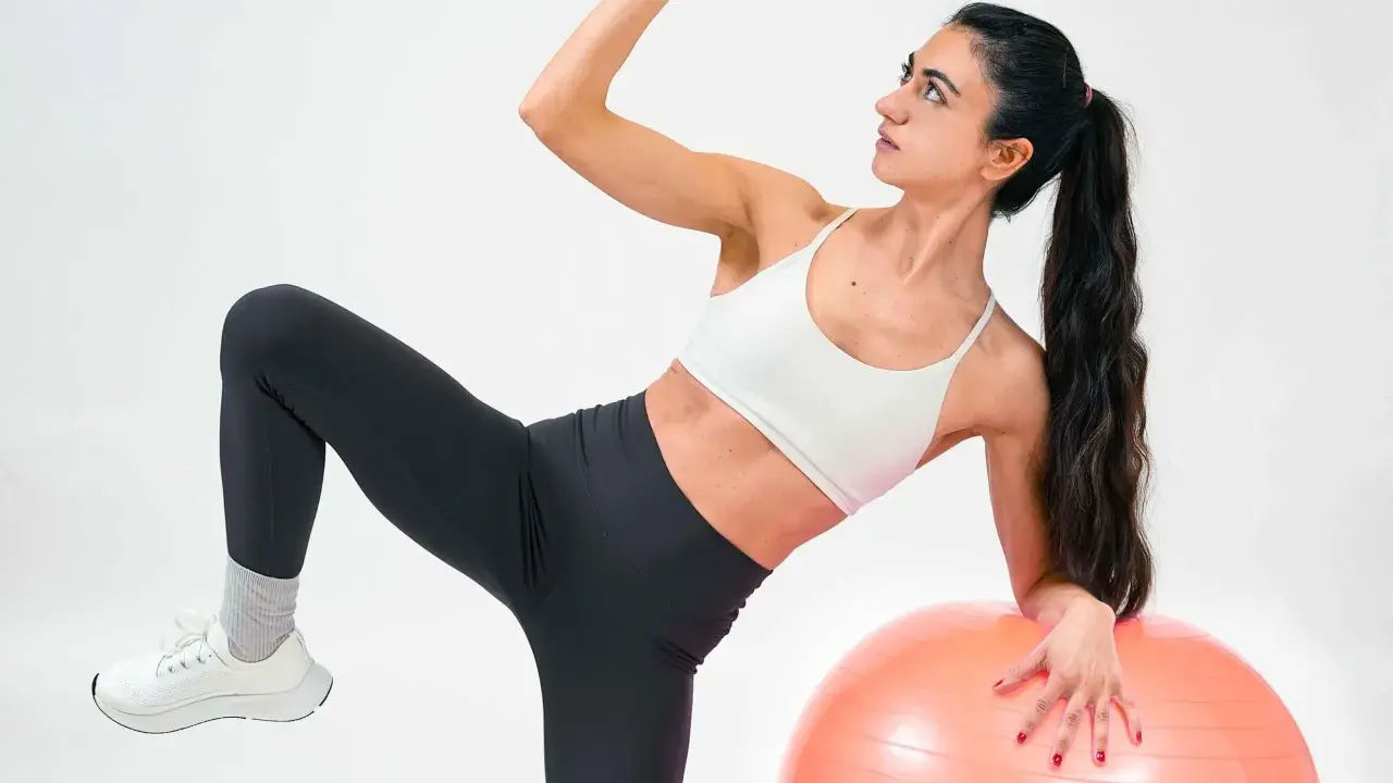 Frau macht Übungen mit Gymnastikball. Sie fragt sich, was ist Kreatin, während sie ihre Muskeln trainiert.