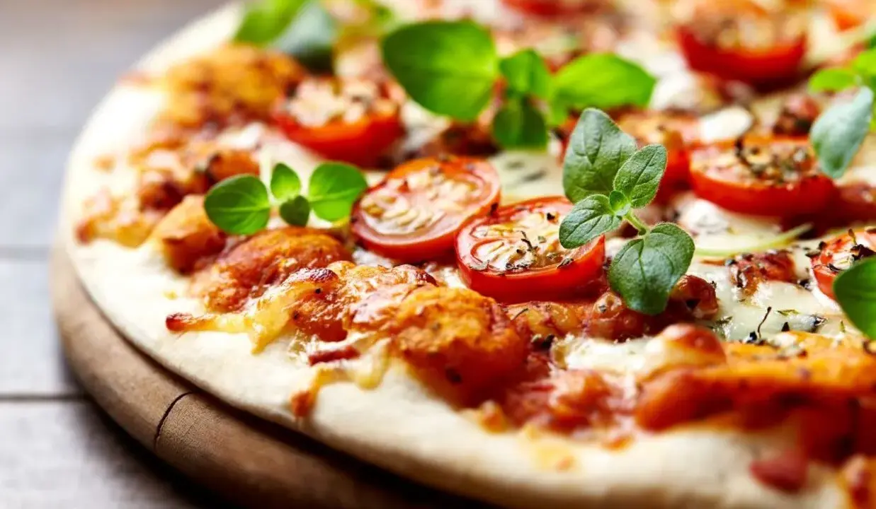 Pyszna pizza bez drożdży z pomidorkami koktajlowymi i świeżą bazylią, idealna na szybki obiad.