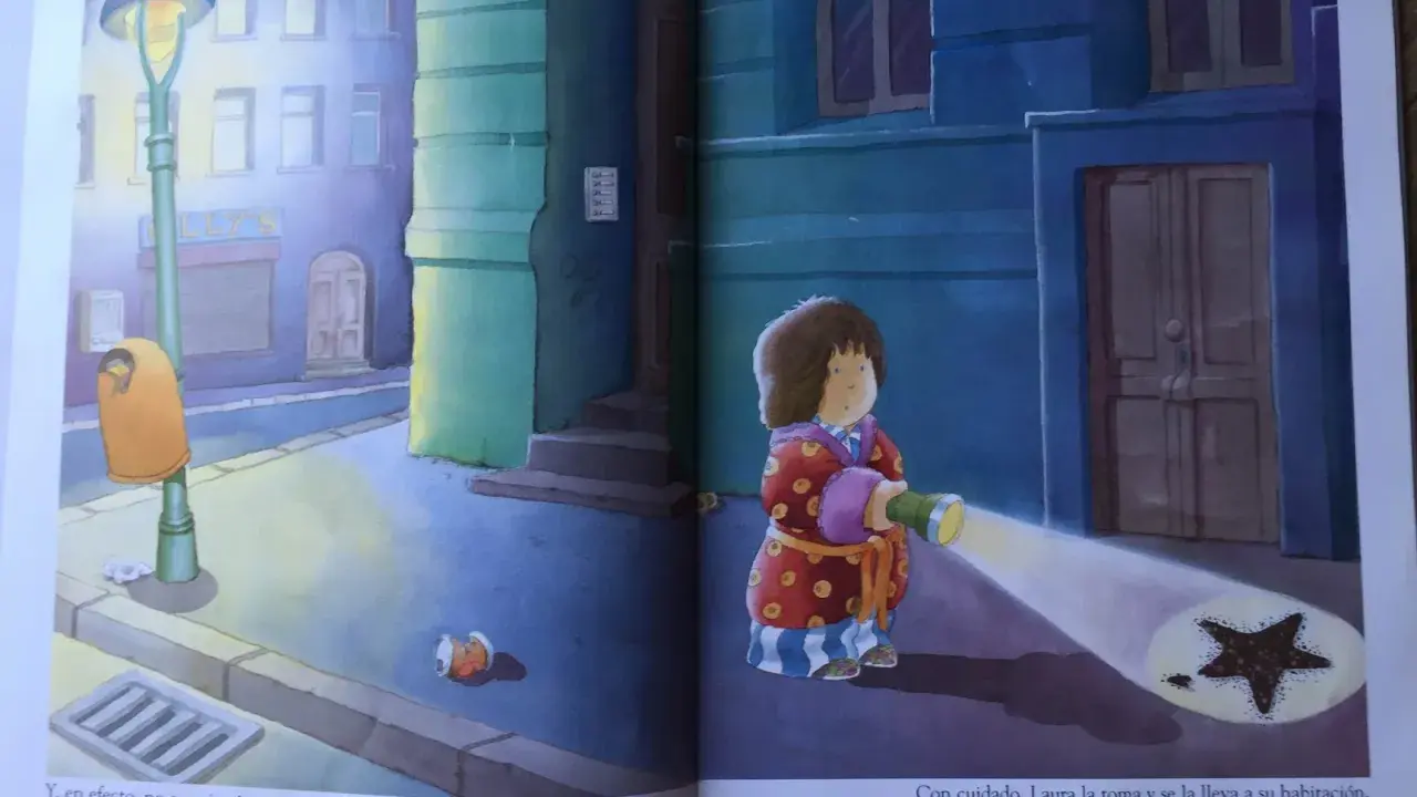 Laura, protagonista de "la estrella de laura cuento", ilumina con su linterna una estrella caída en la acera.