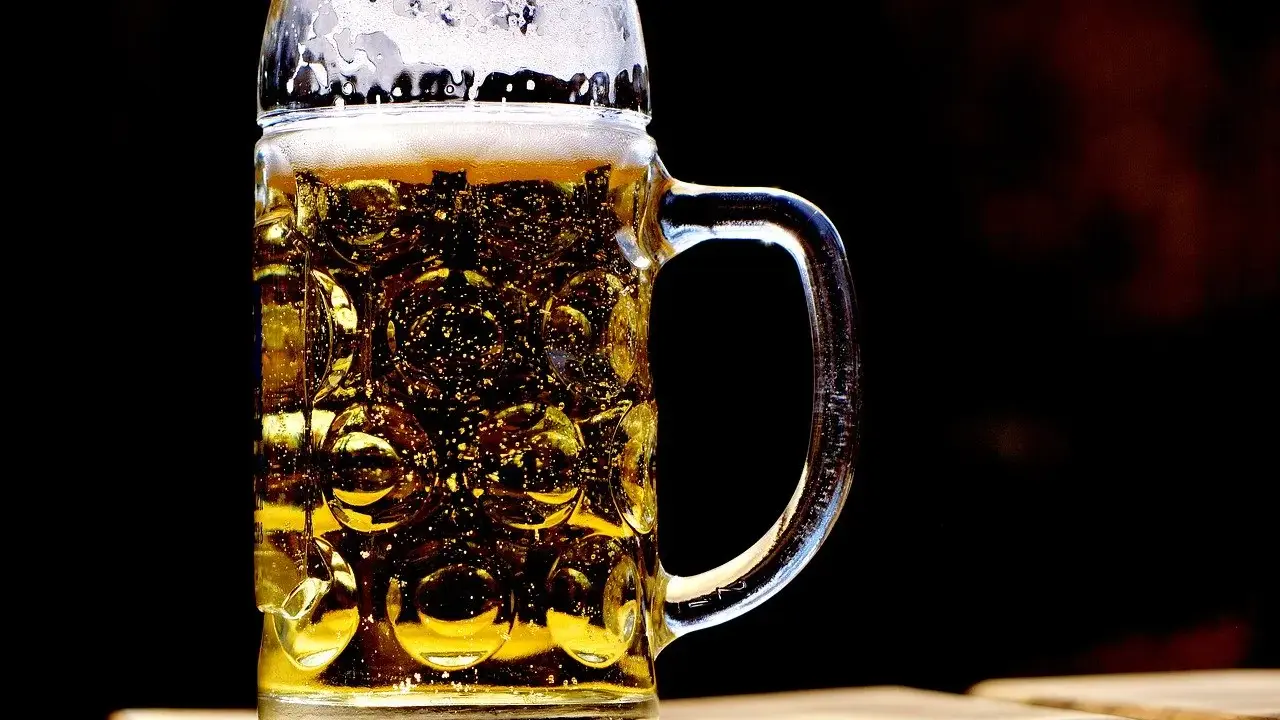 Szklany kufel z piwem, z charakterystycznymi wgłębieniami, to jeden z wielu rodzajów kufli do piwa. Piana i bąbelki dodają mu uroku.