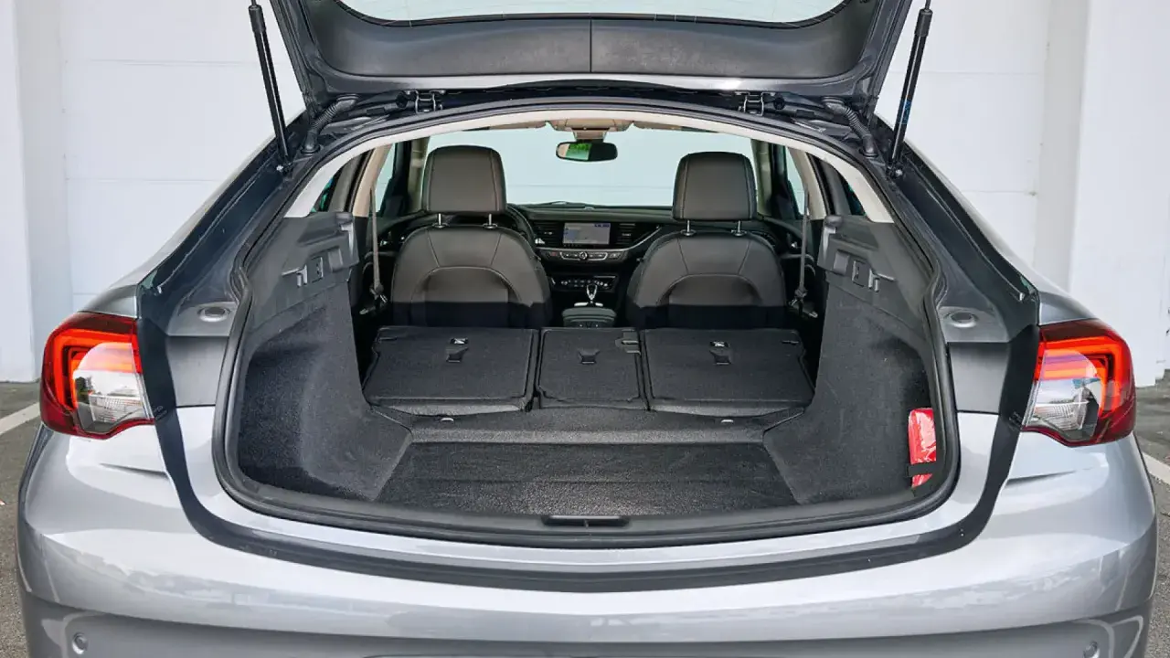 Maletero abierto de un Opel Insignia gris, mostrando asientos traseros abatidos y espacio de carga. Ideal para conocer las medidas del maletero.