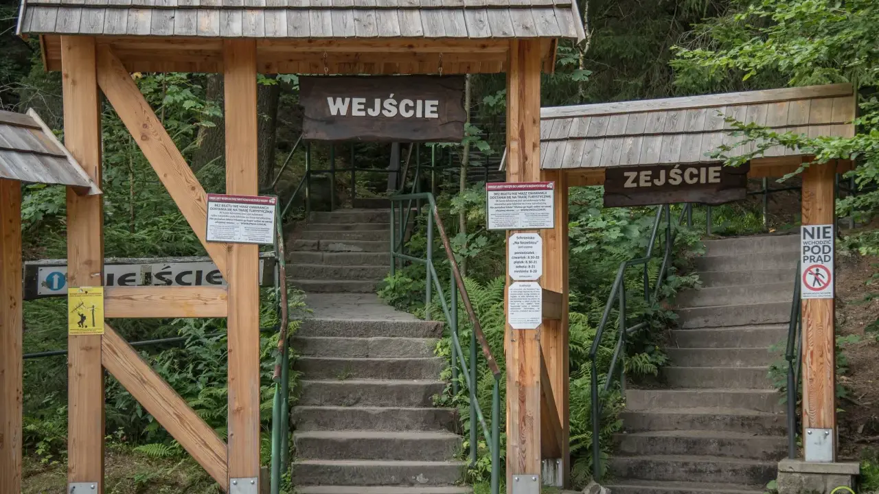 Kamienne schody prowadzą do wejścia na teren Szczelińca Wielkiego. Drewniane bramy z tablicami informacyjnymi zapraszają do zwiedzania.