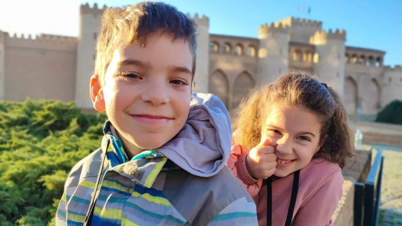 Dos niños sonríen frente al Palacio de la Aljafería, un lugar genial que ver en Zaragoza con niños.