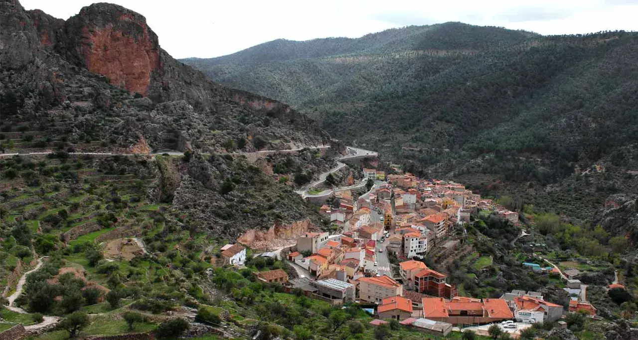 Pueblo encajado en un valle, con casas de tejados naranjas y una carretera serpenteante. Descubre qué ver en Ayna, un rincón pintoresco.