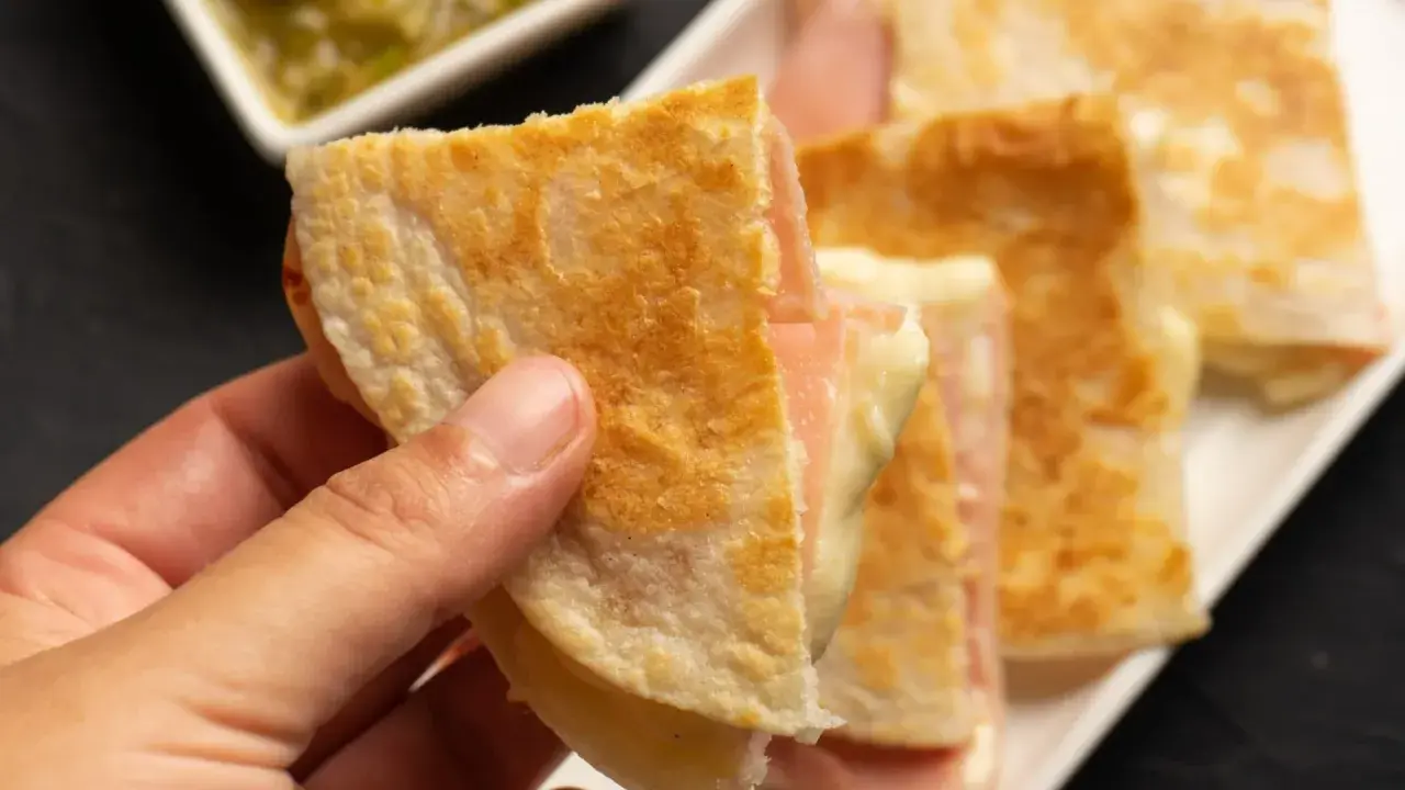Ciepłe quesadille z szynką i serem, idealne na szybką kolację. Obok sos.
