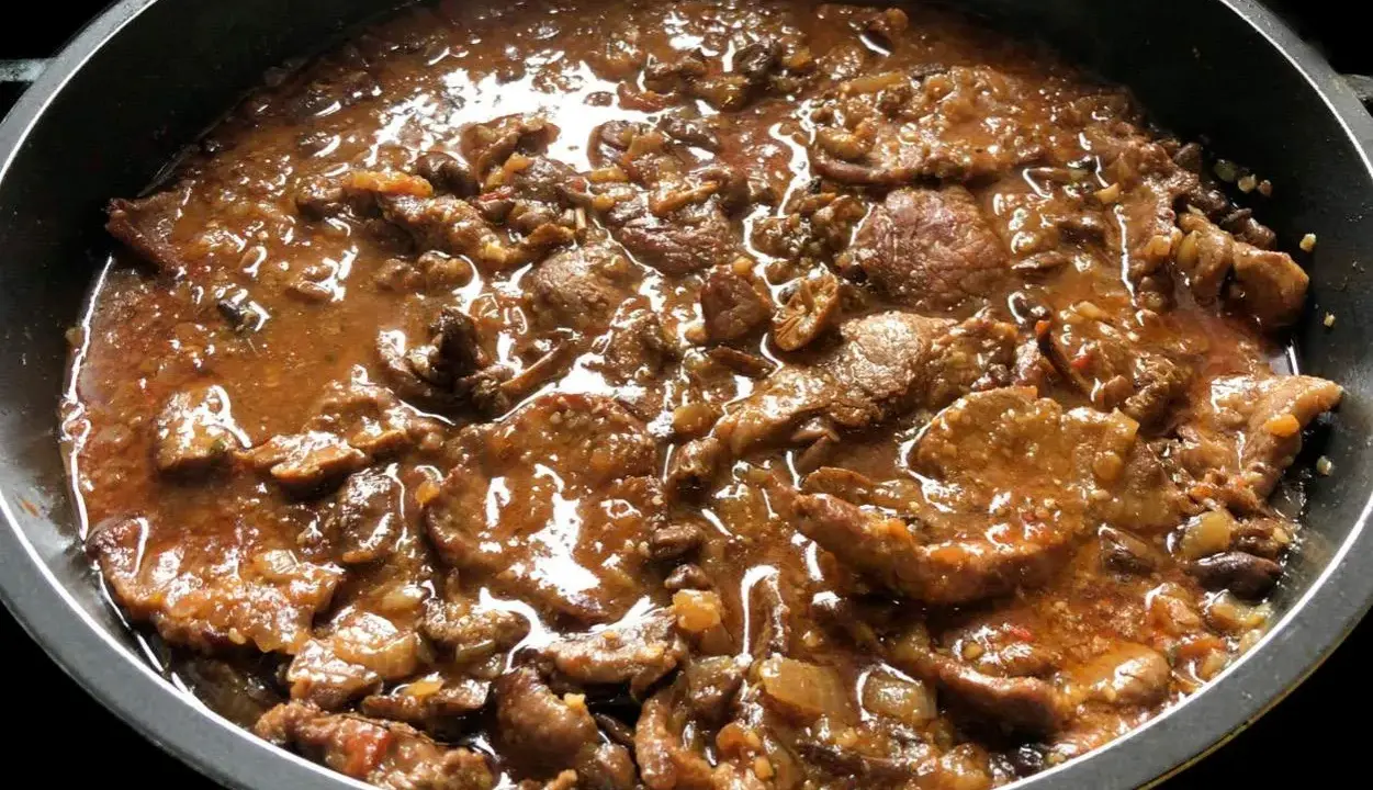 Fricandó de ternera cocinándose en una sartén, con trozos de carne tierna en una salsa espesa y aromática.