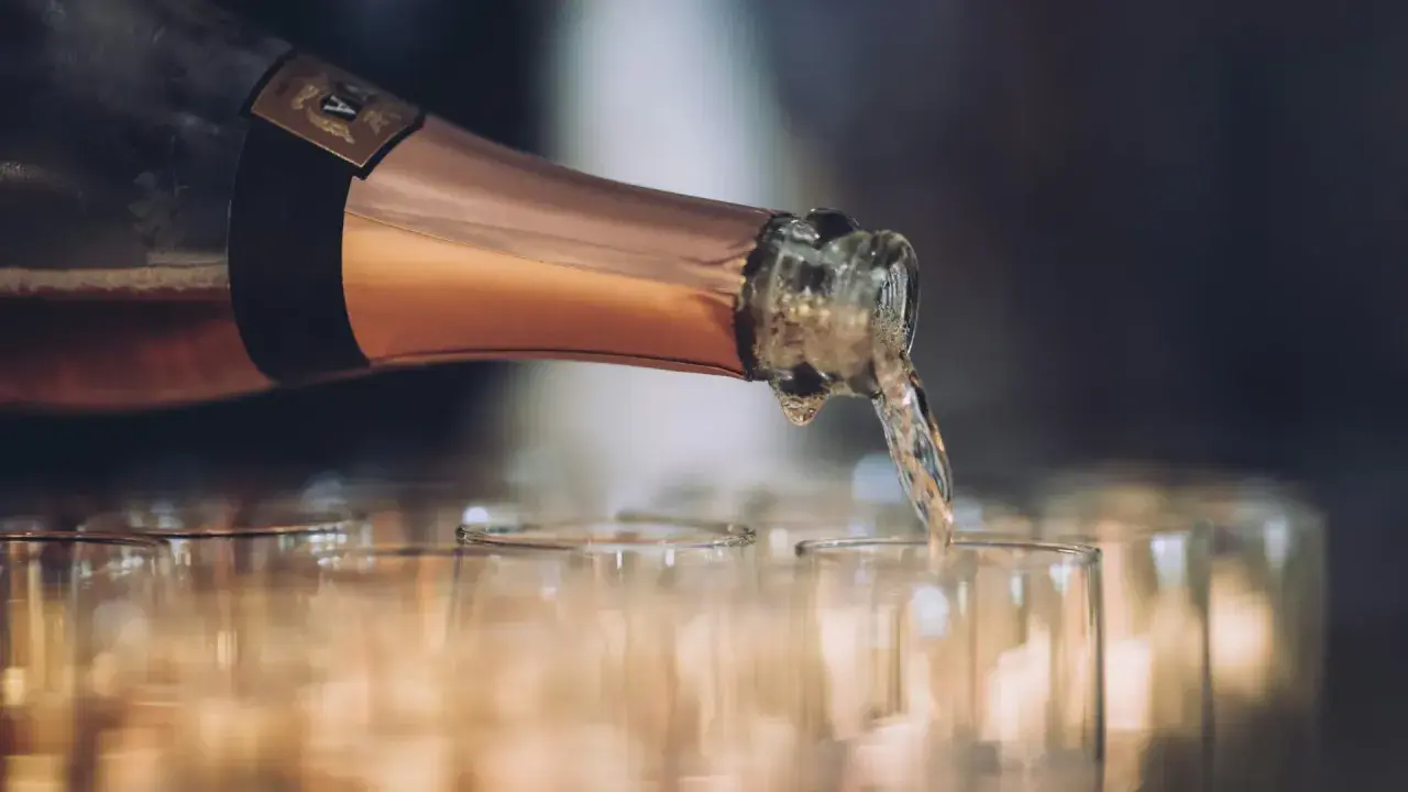 En flaska hälls upp i glas, det ser ut att bli gott bubbel.