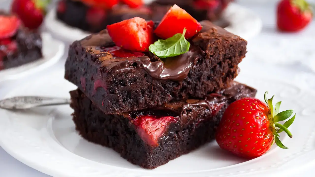 Pyszne brownie z truskawkami, polane czekoladą i ozdobione świeżymi owocami. Idealne na deser!