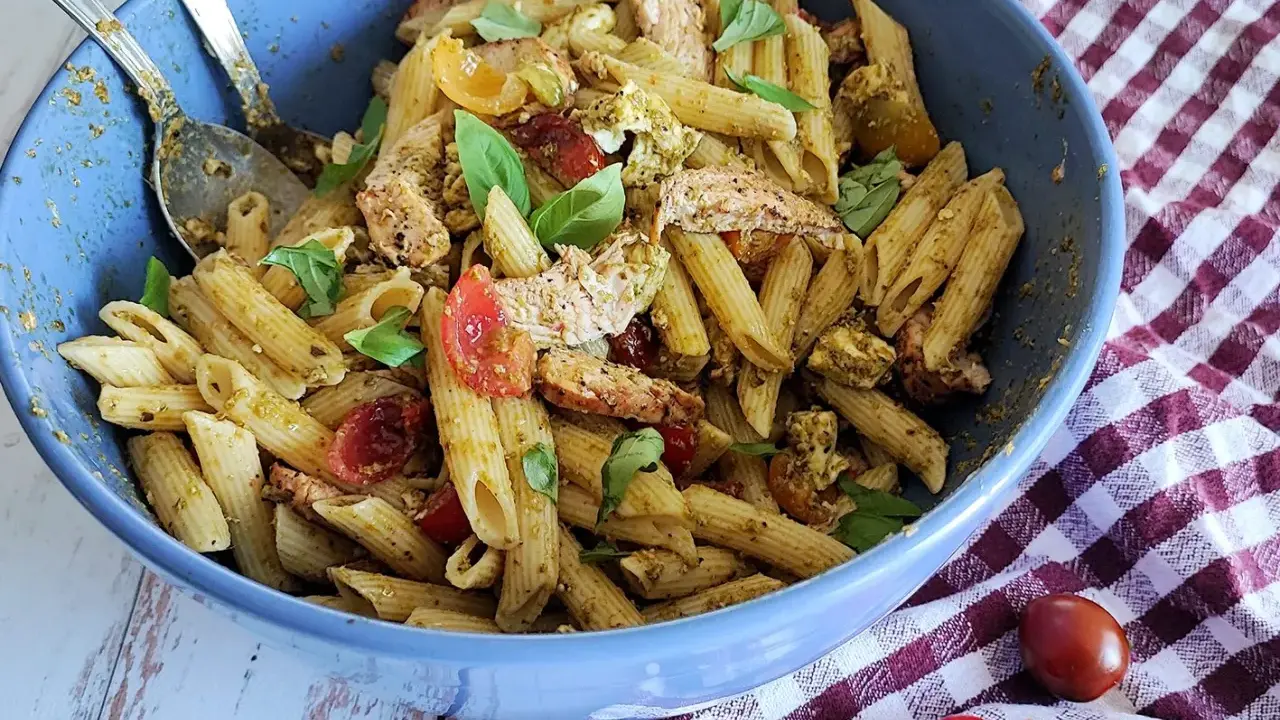 Un plat généreux de penne à la salade pesto, garni de poulet effiloché, tomates cerises et basilic frais. Un délice pour les papilles !