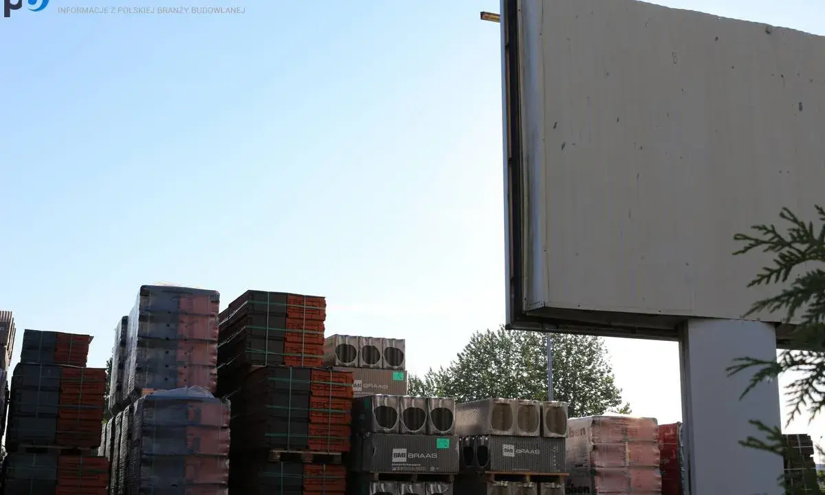 Stosy dachówek i materiałów budowlanych pod pustym billboardem. Reklama na budynku inaczej, czekająca na nowe hasło.