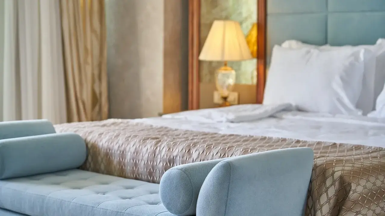 Elegancka sypialnia hotelowa z wygodnym łóżkiem i sofą. Spełnia wszelkie **hotel 4 gwiazdki wymagania** dotyczące komfortu i stylu.