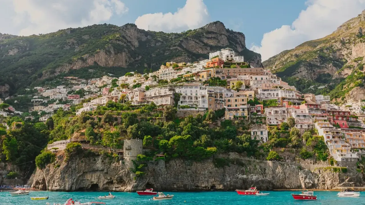 Positano, un gioiello da scoprire, perfetto per chi cerca cosa vedere a Napoli in un giorno. Case colorate aggrappate alla scogliera, mare azzurro e barche.