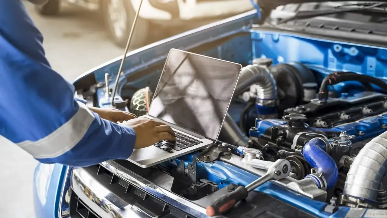 Mechanik z laptopem optymalizuje pracę silnika, przygotowując go do chip tuningu.