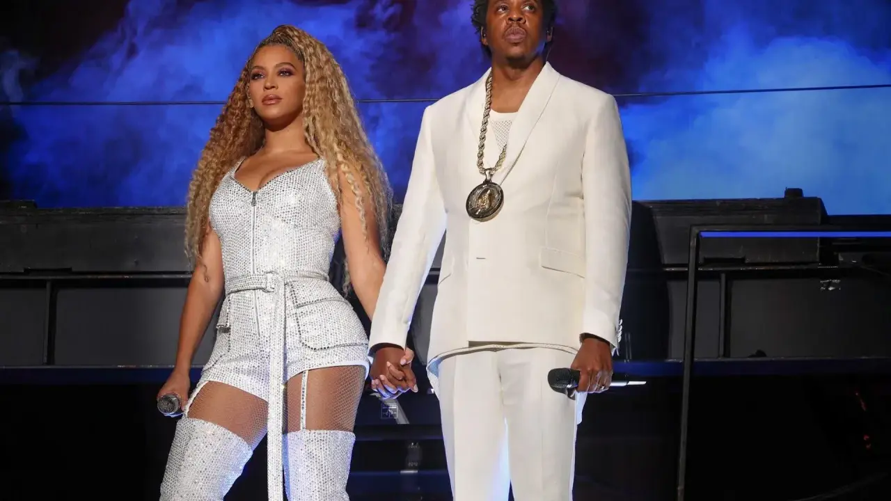 Beyoncé i Jay-Z, symbol sukcesu i majątku, na scenie w błyszczących strojach.