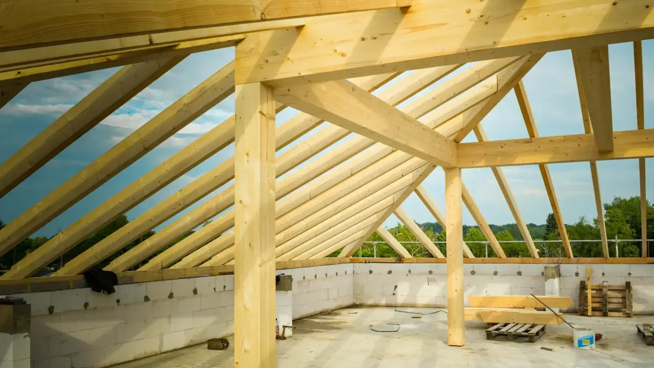 Drewniana konstrukcja dachu w budowie, z widocznymi belkami i krokwi.