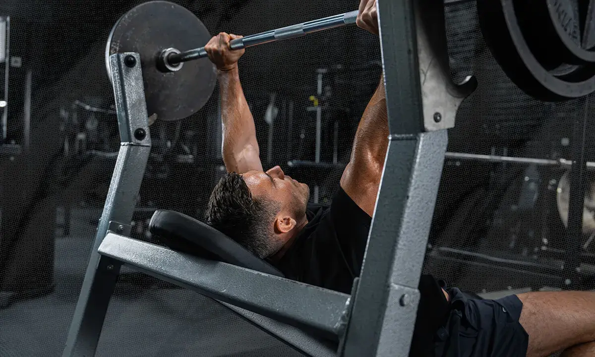Mann beim Bankdrücken, ein wichtiger Teil seines Powerlifting Trainingsplans.