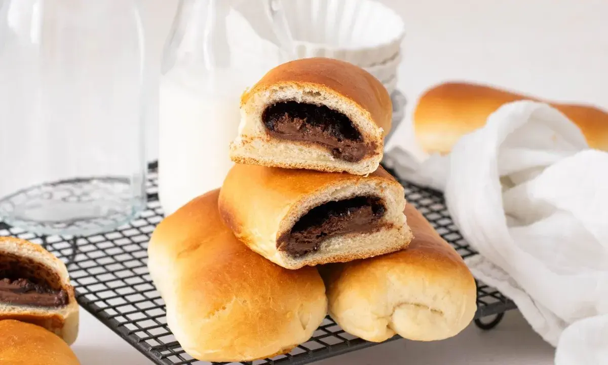 Bollo de chocolate recién horneado, con relleno cremoso, apilado sobre una rejilla.