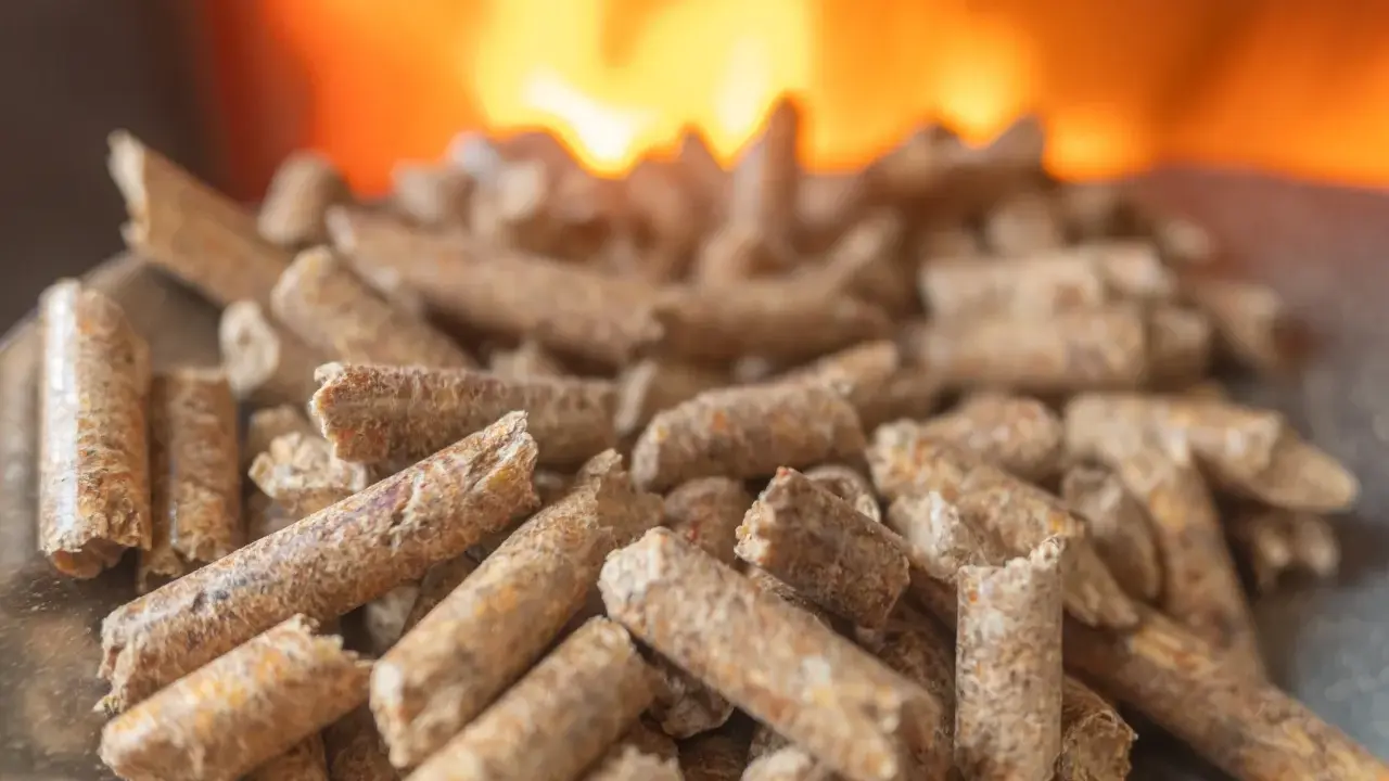 Granulés de bois prêts pour l'installation d'un poêle à granule, avec des flammes chaudes en arrière-plan.